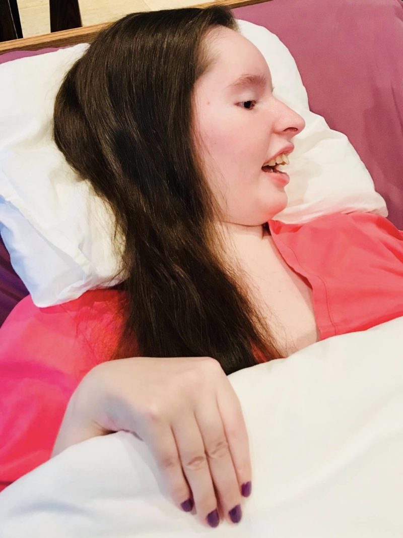Emily in hospital bed with her famous, giant smile