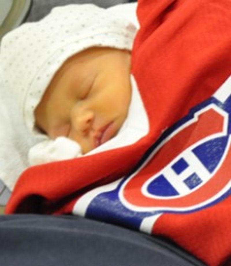 A photo of baby Grace sleeping while wrapped in a large hockey jersey