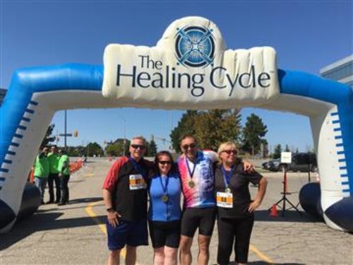 For members of the Emily’s House / PAC Healing Cycle team pose at the starting line/finish line of the bike riding event fundraiser
