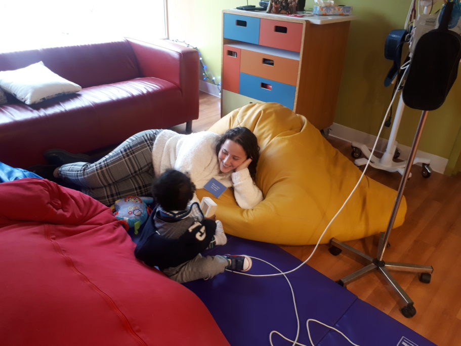 An Emily’s House volunteer smiles and enjoys beanbag time with a toddler