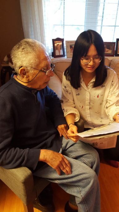 A volunteer reads the newspaper with an adult PAC Community client